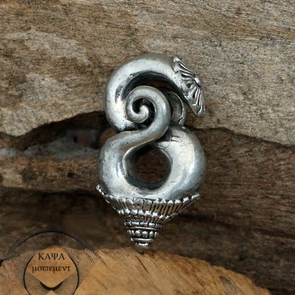 A PENAN BORNEO Heavy Tribal Ear Weight in silver, spiral-shaped with intricate detailing that resembles a coiled serpent, is displayed against a wooden background. Reminiscent of traditional brass ear-weights worn by the Penan Tribe, a watermark in the bottom left corner reads "Kaya Movement.